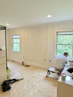 a man is sitting in the middle of a room with white walls and flooring