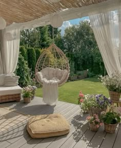 an outdoor area with wicker furniture and flowers on the ground, covered in white drapes