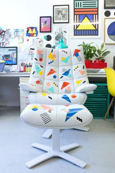 a colorful office chair sitting in front of a desk with lots of pictures on the wall