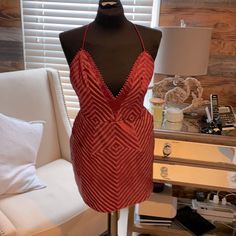 a mannequin wearing a red dress in front of a white chair and window