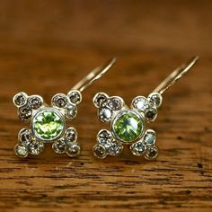 This Georgian era design is memorable for both its elegance and piety. The central peridot is circled by diamonds to form a cross of 14k gold.1" tall by 5/8th" wide with french-backs for pierced ears. Elegant Lime Green Diamond Jewelry, Green Multi-stone Diamond Earrings, Green Diamond Multi-stone Earrings, Green Sterling Silver Diamond Earrings For Anniversary, Anniversary Green Diamond Sterling Silver Earrings, Anniversary Green Diamond Earrings In Sterling Silver, Elegant Pierced Peridot Jewelry, Green Multi-stone Earrings For Anniversary, Madame Bovary