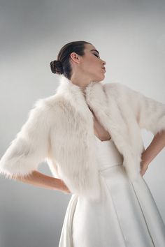 a woman in a white dress and fur stole over her shoulders, looking off to the side