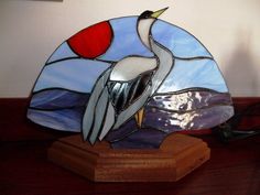 a stained glass bird sitting on top of a wooden table next to a lamp shade