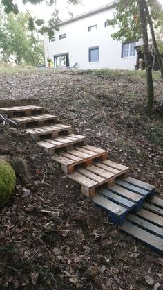 some steps made out of pallets in the woods next to a house and trees