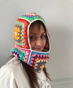 a woman wearing a multicolored crocheted hat and scarf with a hood on her head