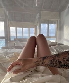 a woman laying in bed with tattoos on her arm