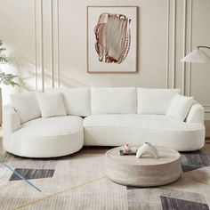 a living room with a large white sectional couch and round coffee table in the middle