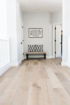 a white room with wood floors and a bench in the center, framed artwork on the wall