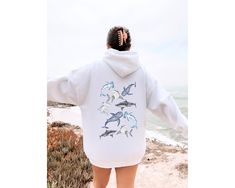 Dive into a sea of style with our Oversized Shark Sweatshirt! This fin-tastic piece is perfect for shark enthusiasts and marine life lovers alike. Featuring intricately embroidered designs of the magnificent whale shark, hammerhead, and bull shark, this sweatshirt is a unique and stylish tribute to these awe-inspiring creatures. Made for comfort and style, it's not just a garment; it's a statement of your passion for sharks and ocean conservation. Whether you're exploring the depths of the sea or enjoying a cozy day indoors, this sweatshirt is a must-have for those who want to make waves with their fashion. Join the movement to save the sharks and showcase your love for marine life with this trendy and comfortable sweatshirt. It's the perfect gift for any shark enthusiast or a great additi Shark Sweatshirt, Vsco Hoodie, Shark Hoodie, Vintage Hoodies, Fall Sweatshirt, Fleece Sweatshirt, Girls Fashion Clothes, Womens Clothing Sizes, Casual Pullover