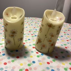 two candles sitting on top of a polka dot table cloth