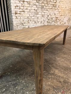 a wooden table sitting in front of a brick wall