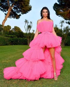 a woman in a pink dress standing on the grass