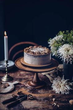 a cake sitting on top of a wooden table next to a candle and some flowers