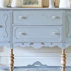 a blue dresser with two white vases on top