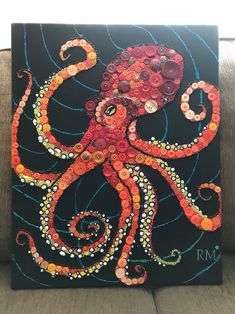 an octopus made out of buttons on a black canvas with blue swirls and circles