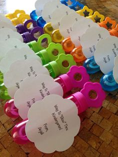 there are many different colored scissors on the table with name tags attached to them,