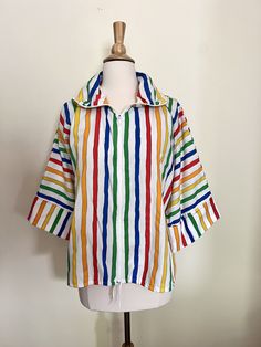 "Vintage 70s Teddi of California zip-front rainbow jacket. Amazing 70s summertime vibes with this crisp, zip front jacket. Wear zipped all the way up, zipped partway, or unzipped. Full sleeves that hit 3/4 of the way down, tie at bottom to cinch. Vertical stripes with horizontal stripes at folded cuffs. Rainbow colors are bright with black edging, making them really pop. Hits at bottom of hips. Material is a cotton/poly blend, size 14, but would best fit up to a modern day M/L. Excellent vintage 70s Shirts Vintage, Collared Tops With Zipper Closure For Spring, Spring Collared Tops With Zipper Closure, Spring Collared Top With Zipper Closure, Retro Multicolor Summer Outerwear, Retro Spring Top With Rainbow Print, Retro Rainbow Print Top For Spring, Retro Rainbow Tops For Spring, Frank Core