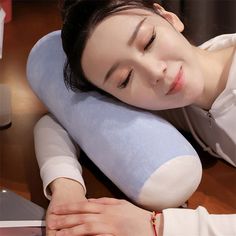 a woman laying on top of a blue pillow next to a laptop computer with her eyes closed