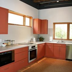 an empty kitchen with orange cabinets and stainless steel dishwasher, sink, stove, microwave and dishwasher