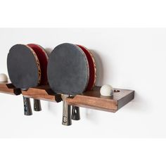 three ping pong paddles on a wooden shelf