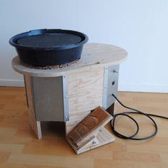 a black pot sitting on top of a wooden table next to a power cord and plugged into an outlet