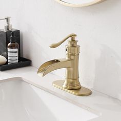 a gold faucet sink with soap dispenser and mirror in the background