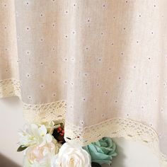 flowers and lace are sitting on the window sill in front of a curtain with polka dots