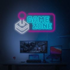 a computer desk with a neon game zone sign above it