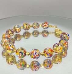 "Murano glass bracelet of 8mm beads with genuine 24k gold foil within each bead. Colorful and whimsical jewelry with an elegant touch! These glass beads are sourced from Artisans in Murano, Italy in Venice where they apply age old techniques to create these tiny works of art. Each bead is so charming with colors of red, orange, blue and yellow splattered within. Tiny gold beads accent the glass beads. The bracelet measures 7.25 inches with a Vermeil gold lobster claw clasp. ( Please measure your Venetian Glass Jewelry, Gold Bracelets With 8mm Beads For Party, Party Gold Bracelet With 8mm Beads, Multicolor Gold Bangle Bracelet As A Gift, Multicolor Bangle Gold Bracelet As A Gift, Colorful Glass Beaded Bracelets, Yellow Czech Glass Bracelets With Round Beads, Glass Beaded Bracelets With Spacer Beads, Gold Crystal Bracelet With Colorful Beads For Spiritual Use