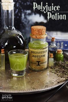 bottles and glasses filled with green liquid on top of a metal tray