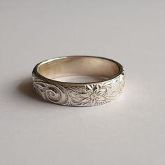 This silver ring has an engraved band with a floral pattern The width of the shin (band) is 5 mm and is 1.7 mm thick. Silver Carved Engraved Ring For Anniversary, Silver Engraved Carved Ring For Anniversary, Classic Silver Carved Engraved Ring, Elegant Engraved Ring With Round Band, Elegant Engraved Round Band Ring, Elegant Silver Carved Engraved Ring, Classic Engraved Flower Ring For Anniversary, Elegant Engraved Silver Flower Ring, Elegant Stamped White Gold Engraved Ring