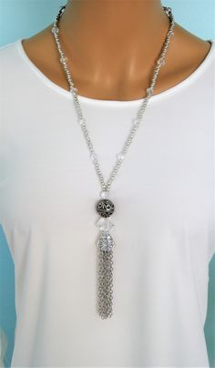 "Four different styles of silver beaded tassel necklaces to choose from, designed and handmade by Ralston Originals. I made all the tassels with silver chains, and covered each in a beautiful antique silver metal bead cap. The first beaded necklace (Pictures 1-3), is made with a very unique and beautiful large silver bead, with many tiny crystal inlaid accents. The necklace is also made with a large antique silver crystal roundel, and a large clear crystal bead. The beaded chain on the necklace Handmade Silver Long Tassel Necklace, Silver Bohemian Lariat Tassel Necklace, Adjustable White Tassel Necklace, Adjustable Beaded Chain Tassel Necklace As Gift, Adjustable Long Tassel Necklace With Dangling Beads, Adjustable Silver Long Tassel Necklace, Adjustable Long Silver Tassel Necklace, Silver Adjustable Long Tassel Necklace, Adjustable Tassel Necklace With Dangling Beads As Gift