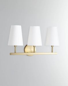 three lamps are on the wall in front of a white background and one light is gold