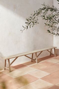 a wooden bench sitting on top of a tiled floor next to a potted plant