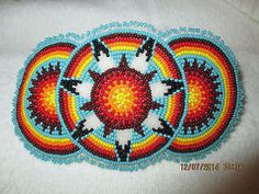 a close up of a beaded object on a white surface with an orange and blue design