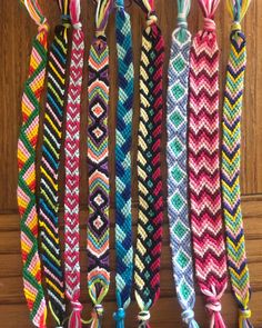 several colorful bracelets hanging from hooks on a wooden door hanger with tassels