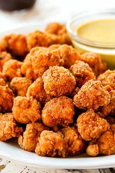 a white plate topped with fried food next to dipping sauce