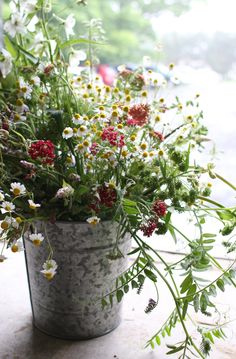 a bucket filled with lots of flowers sitting on top of a window sill next to a