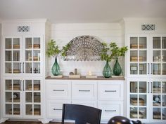 a kitchen with white cabinets and green vases