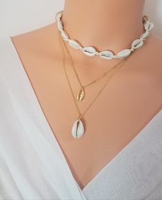 "Cowrie shell necklace, Choker necklace, Surfer necklace, Hawaiian necklace, Surfer Girl necklace, Friendship necklace, Cowrie necklace ★Details: This listing is for your choice of a single necklace. ✦ Cowrie Gold Pendant Necklace / Beaded Chain/ 16\" ✦ Real Cowrie Pendant Necklace / Plain Chain/ 18\" ✦ Real Cowrie Choker: The necklace is secured by tying knot at the back of the neck. This choker necklace is fully adjustable with total length up to 35 inches. The shell portion of the necklace is Shell Clavicle Chain Jewelry For Beach, Elegant Shell-shaped Charm Necklaces For Beach, Beach Shell Clavicle Chain Jewelry, White Shell Charm Necklaces For The Beach, White Shell Charm Necklace As Gift, Beach Shell-shaped Necklace With Clavicle Chain, White Shell Charm Necklace For Gift, Shell-shaped Clavicle Chain Necklace For Beach, Clavicle Chain Shell Necklace For The Beach