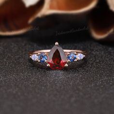 Vintage Pear Shaped Garnet Engagement Ring Unique Moonstone Rose Gold Wedding Ring Red Gemstone Blue Sapphire Cluster Bridal Ring For Women RING DESCRIPTION ✦Engagement Ring ✴Center Stone - Garnet Shape - Pear Cut Size - 6x8mm ✴Side Stones - Sapphire & Moonstone Shape - Round & Pear Cut Size - 3mm*2 & 2x3mm*2 ✴Band Width - About 1.7mm ✴Ring Metal: Available in rose gold plated, yellow gold plated, 925 sterling silver, 10k or 14k solid rose, yellow or white gold. MAKING & SHIPPING ✦PAYMENT PLAN ♡ Garnet And Aquamarine Ring, Elegant Red Multi-stone Sapphire Ring, Red Multi-stone Sapphire Ring, Red Multi-stone Diamond Jewelry, Multi-stone Pear-shaped Sapphire Jewelry, Red Diamond Gemstones For Wedding, Red Pear-shaped Ruby Ring With Center Stone, Wedding Pear-shaped Red Ruby Ring, Pear-shaped Sapphire Multi-stone Jewelry