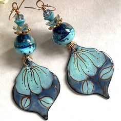 Gorgeous long blue earrings! Enamel by a great artisan paired with a beautiful artisan lampwork bead. 18K gold accent added by hand. Different Czech glass flowers, Swarovski faceted rondelles and gold accents give a touch of sparkling and a rich look. All these chic and unique elements are suspended on gold filled hooks making these earrings allergy free. Blue and gold in different textures and shapes give those earrings a special bohemian and romantic vibe. They are about 3 1/2'' long from the top of ear wire and they are suspended on gold filled hooks. In all my photos, I am trying to depict colors as accurate as possible, but please be aware that colors can appear different on each monitor. I'm sorry but due to the width of the czech lampwork bead, the shipping in Canada is higher than Artisan Blue Earrings, Artisan Handmade Blue Earrings, Handmade Artisan Blue Earrings, Artsy Blue Teardrop Earrings, Artistic Blue Czech Glass Jewelry, Artistic Hand Painted Blue Jewelry, Artisan Blue Earrings With Artistic Design, Blue Bohemian Earrings With Artistic Design, Bohemian Blue Earrings With Artistic Design