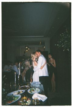 a bride and groom are kissing in front of their guests at a wedding reception with food on the table