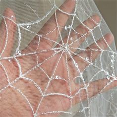 someone is holding their hand in front of a net with spider webs on it