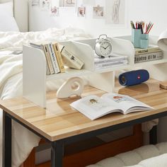 a desk with books, an alarm clock and other items on it in a bedroom