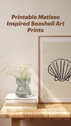 a vase filled with white flowers sitting next to a framed print on top of a wooden table