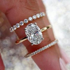 a woman's hand with three different rings on her fingers and one ring in the middle