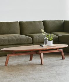 a living room with a couch, coffee table and vase on the floor in front of it