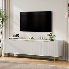 a large flat screen tv mounted to the side of a white cabinet in a living room