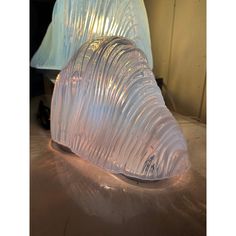 an object made out of plastic sitting on top of a metal table next to a lamp